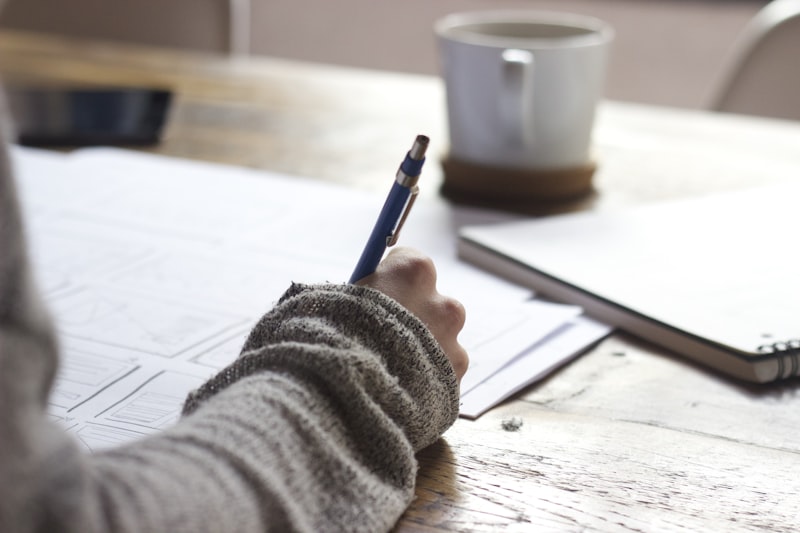 Persona escribiendo una lista de verificación en un cuaderno, preparando la documentación para un proyecto
